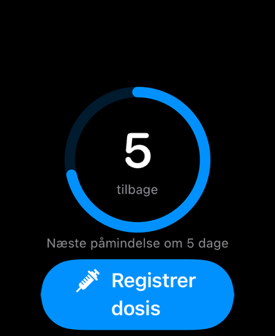 Dial på Apple Watch med en cyklusring, der tæller dage til næste dosis, næste påmindelse og en knap til at registrere